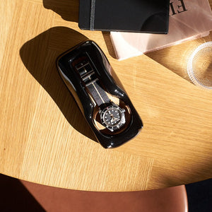 A watch holder with a Tudor Black 58 on a wood desk