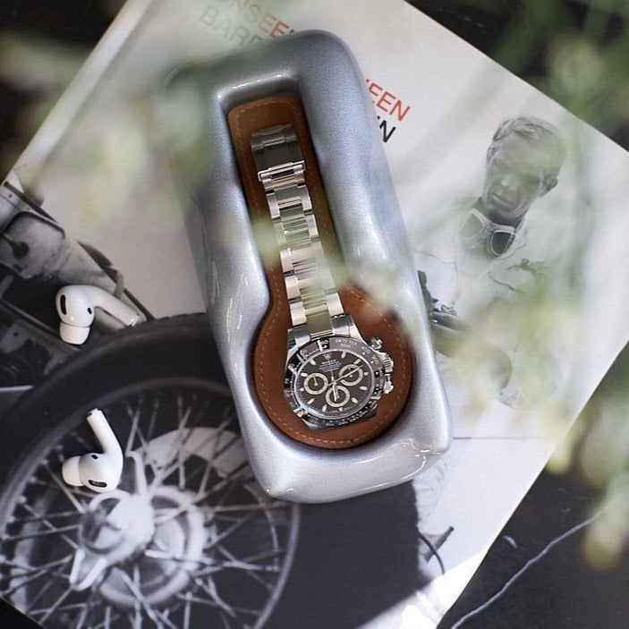 Watch holder in silver on bedside tableA Glacier Silver watch holder with a Rolex Daytona in it sitting on a marble bedside table