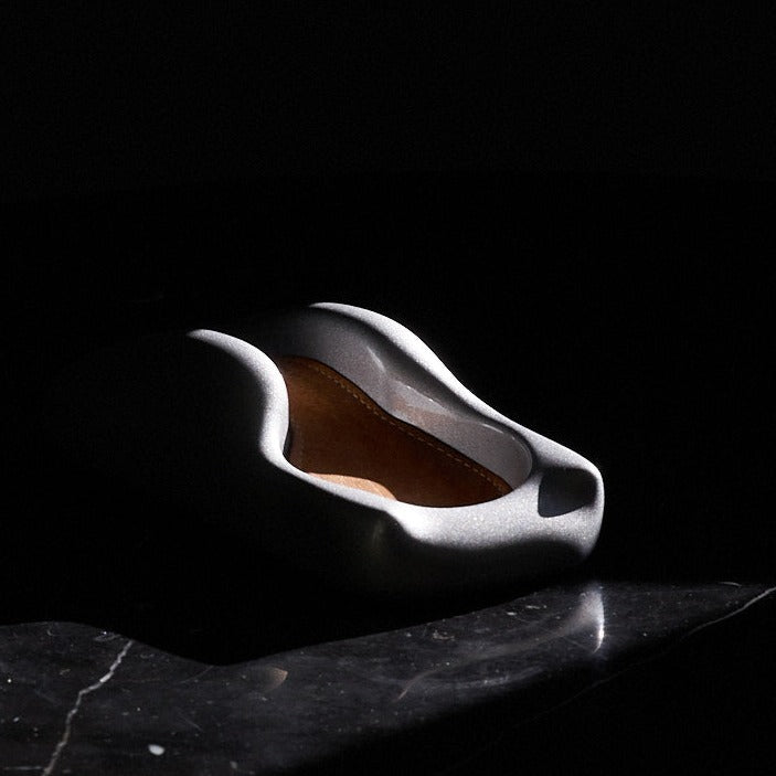 A Glacier Silver watch holder sitting on a marble bedside table