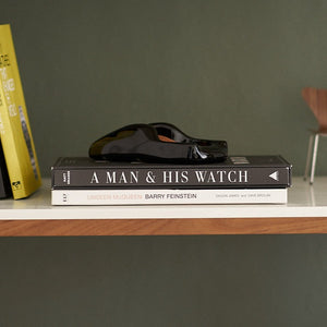 A watch holder decoratively placed on a book shelf 